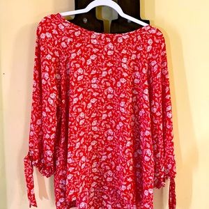 Red blouse with white floral accents. Tie closure on sleeves.